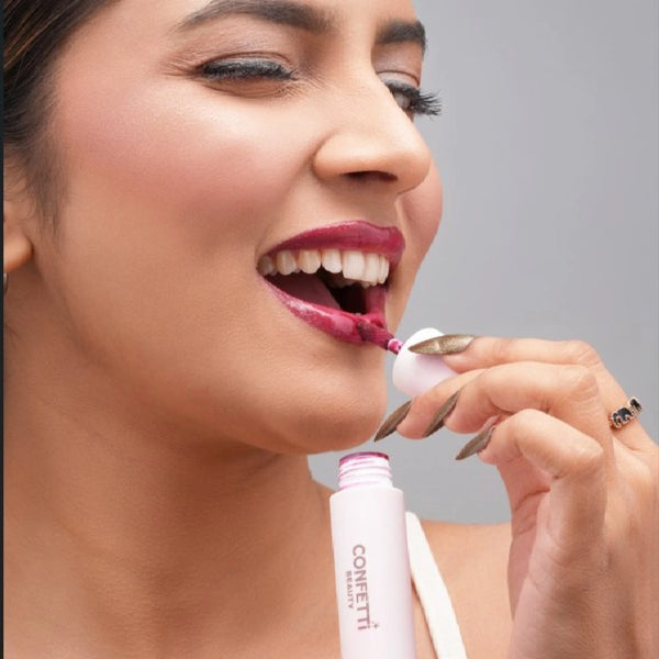 Woman applying Phool Key lip gloss with applicator wand